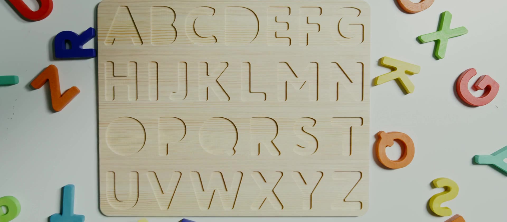 A child fitting the letter A into a wooden alphabet board